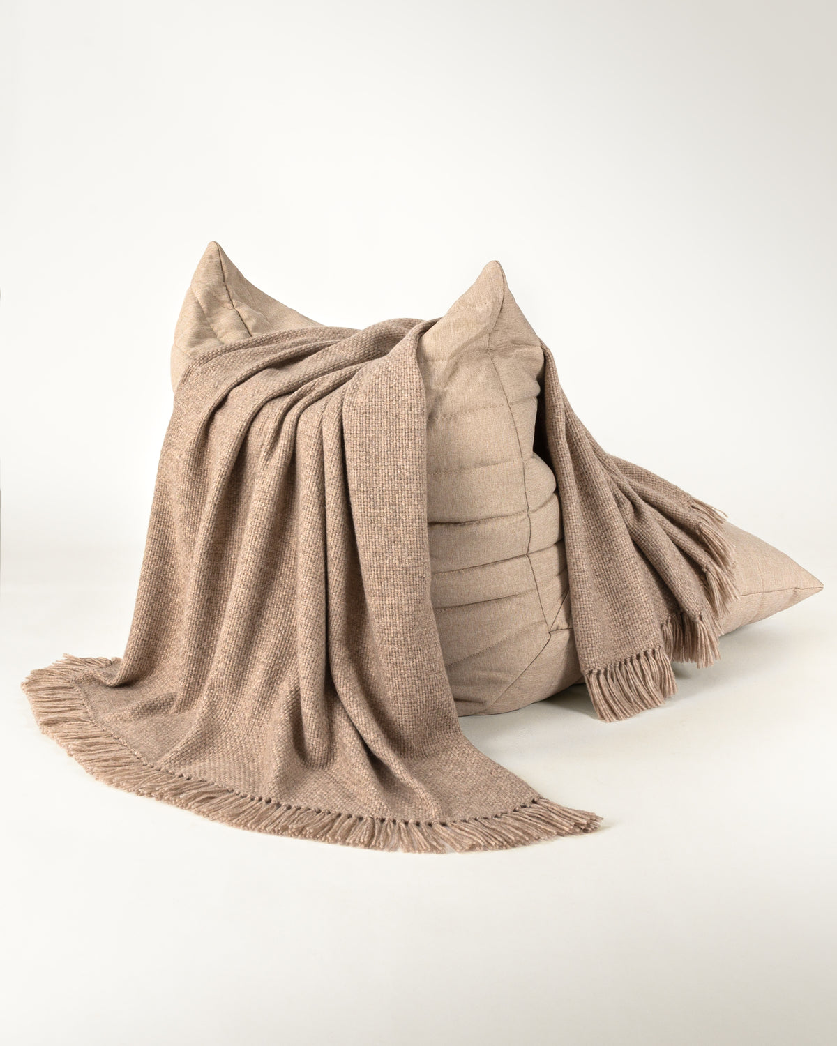 Normy Alpaca Blanket in clay draped over a chair, set against a clean white studio background.