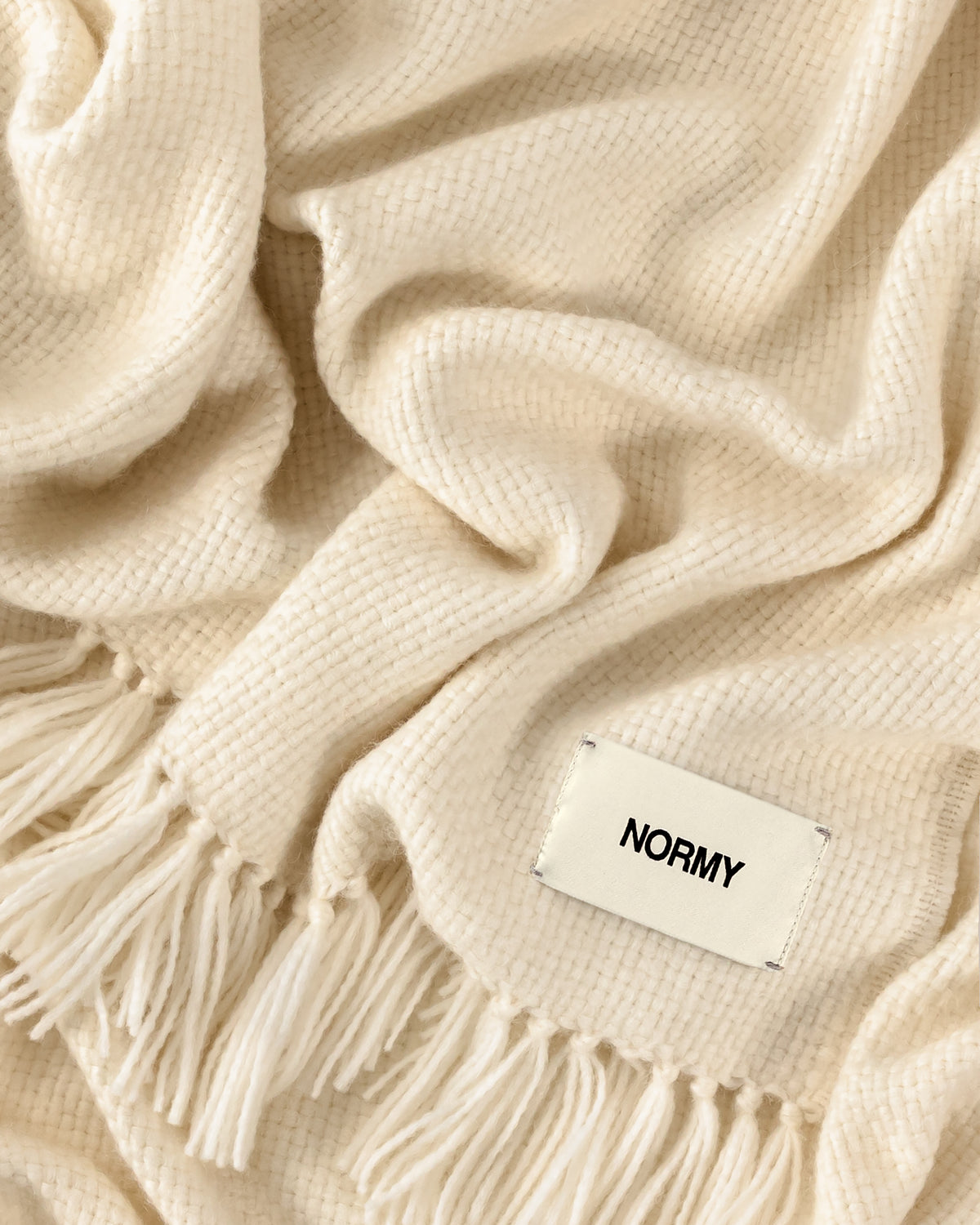 A close-up of Normy Alpaca Blanket in moon with a small white label reading 'NORMY'.