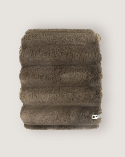 Dimensional faux fur blanket in fungi folded against a neutral background