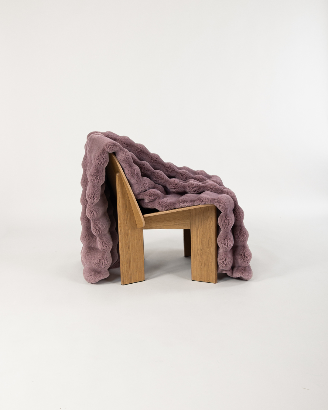Dimensional faux fur blanket in lilac draped on wooden chair