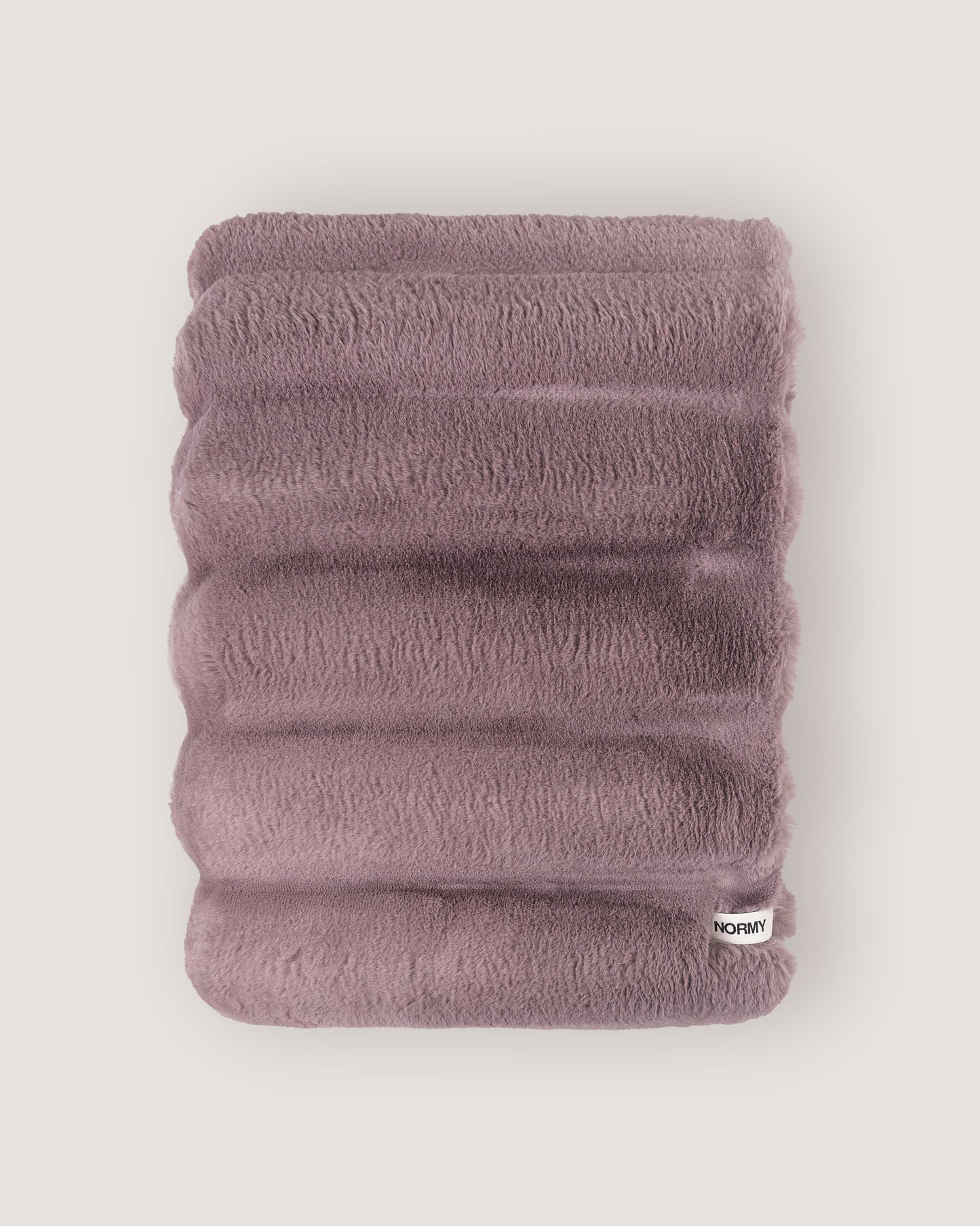 Dimensional faux fur blanket in lilac folded against a neutral background