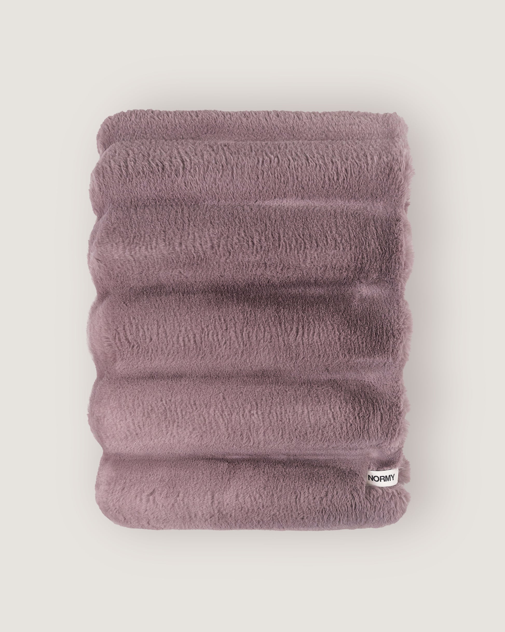 Dimensional faux fur blanket in lilac folded against a neutral background