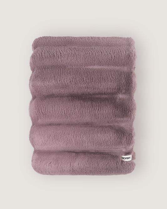 Dimensional faux fur blanket in lilac folded against a neutral background
