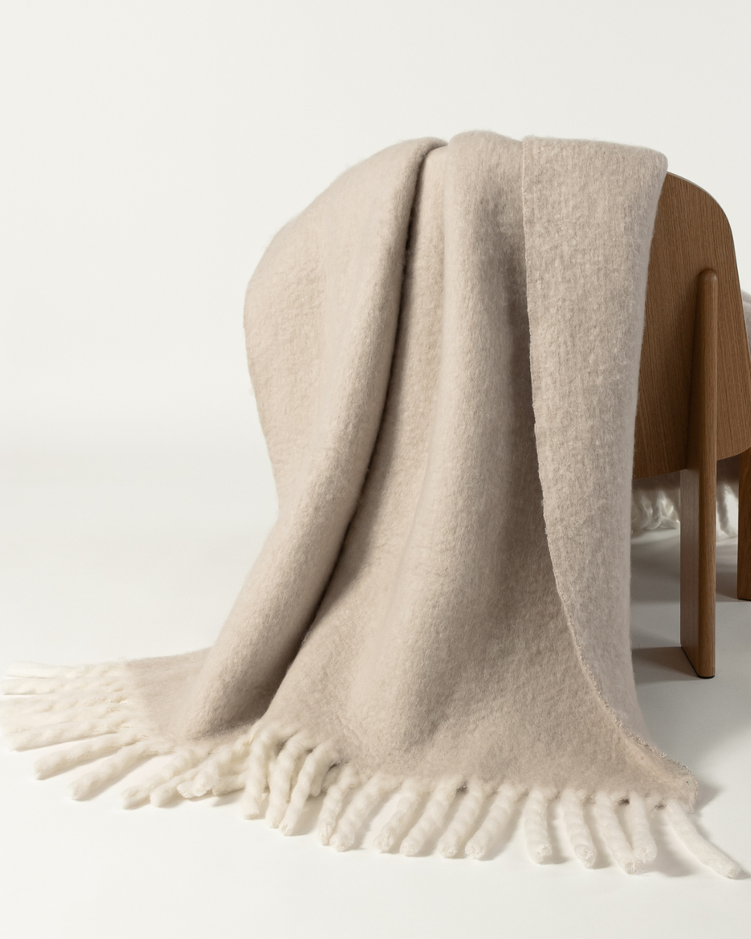 Faux mohair blanket in clay/moon draped over wooden chair