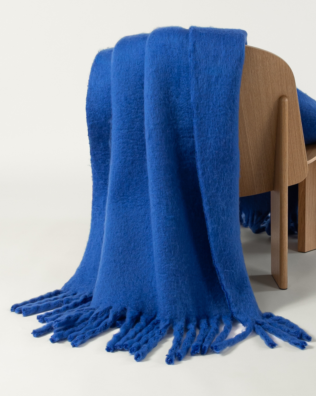 Faux mohair blanket in cobalt draped on wooden chair