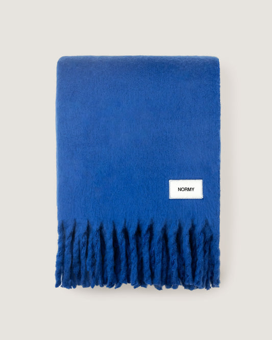 Faux mohair blanket in cobalt folded against a neutral background
