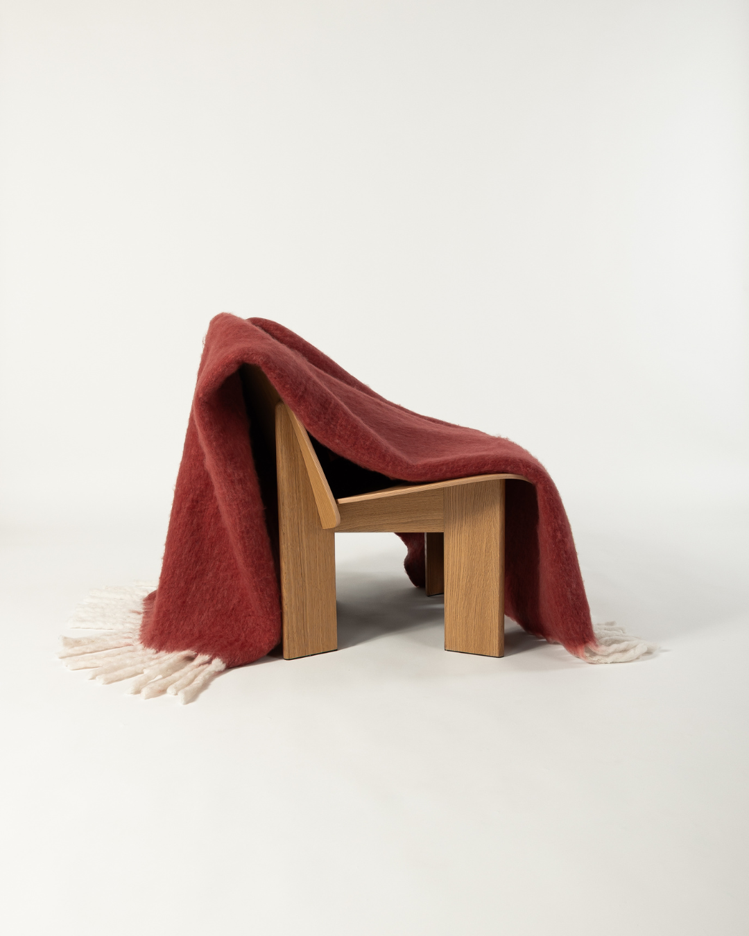 Faux mohair blanket in pomegranate/moon draped on wooden chair