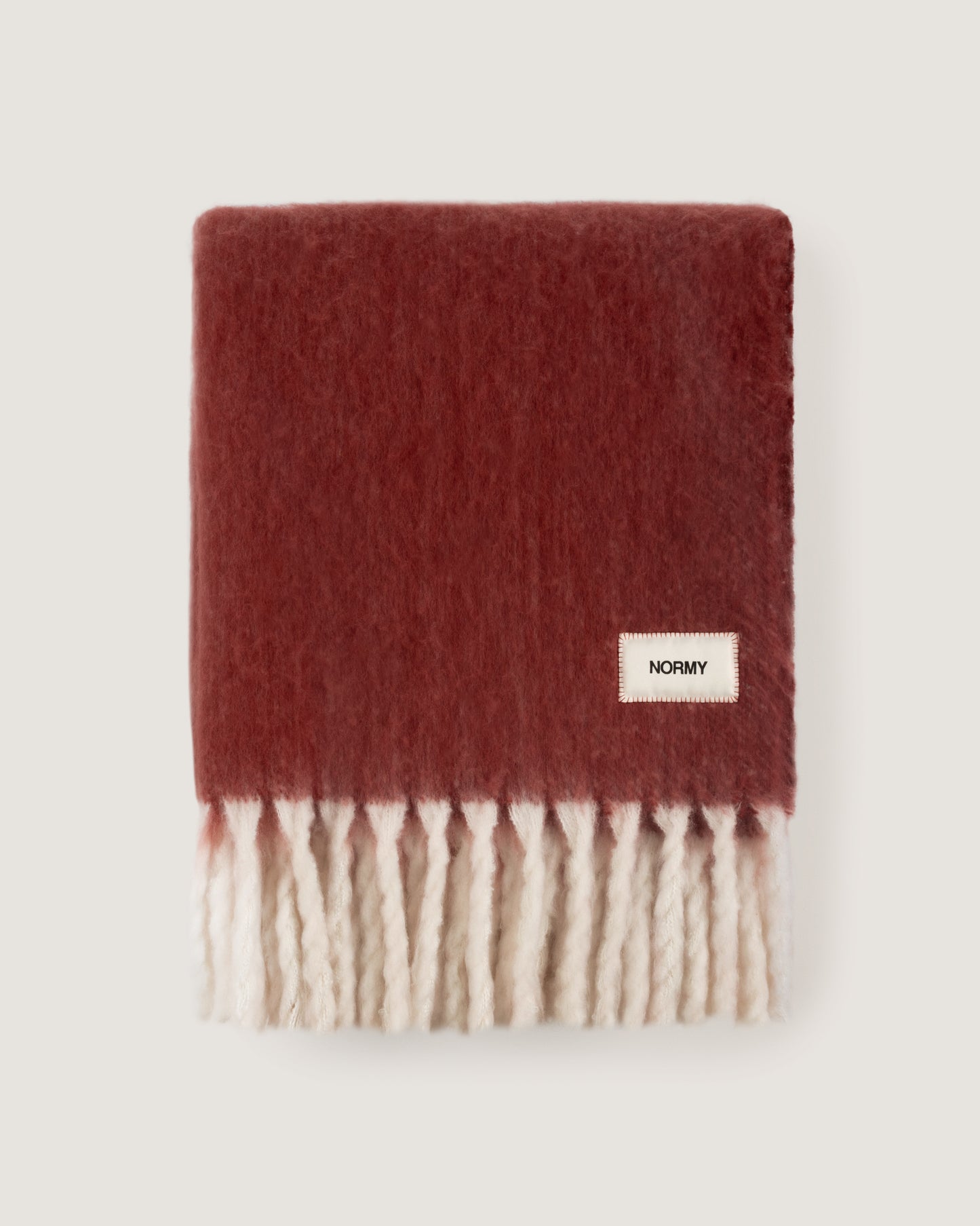 Faux mohair blanket in pomegranate/moon folded against a neutral background