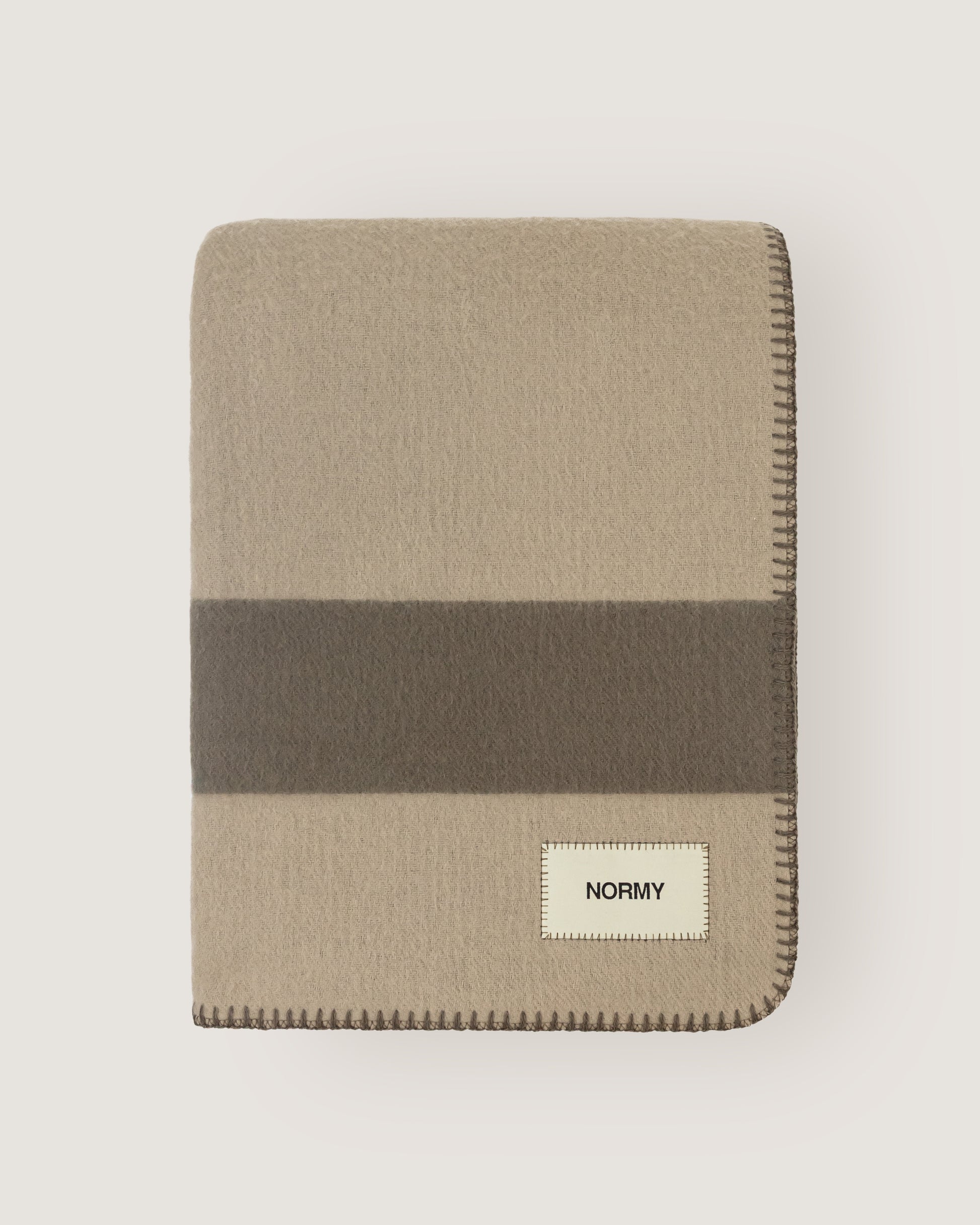Merino wool blanket in clay/fungi folded against a neutral background