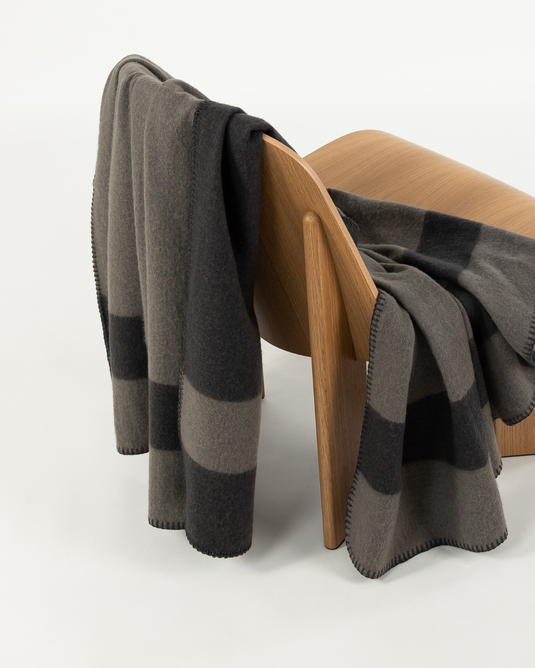 Merino wool blanket in peak/caviar draped over a wooden chair
