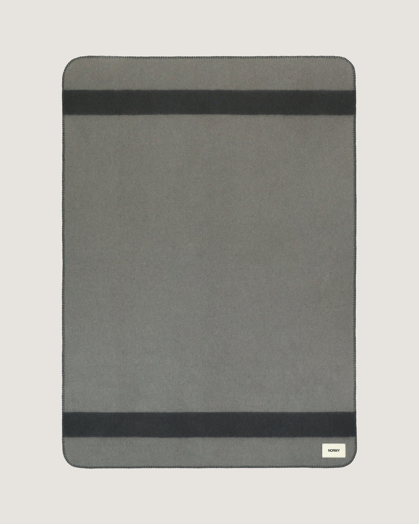 Merino wool blanket in peak/caviar flat against a neutral background
