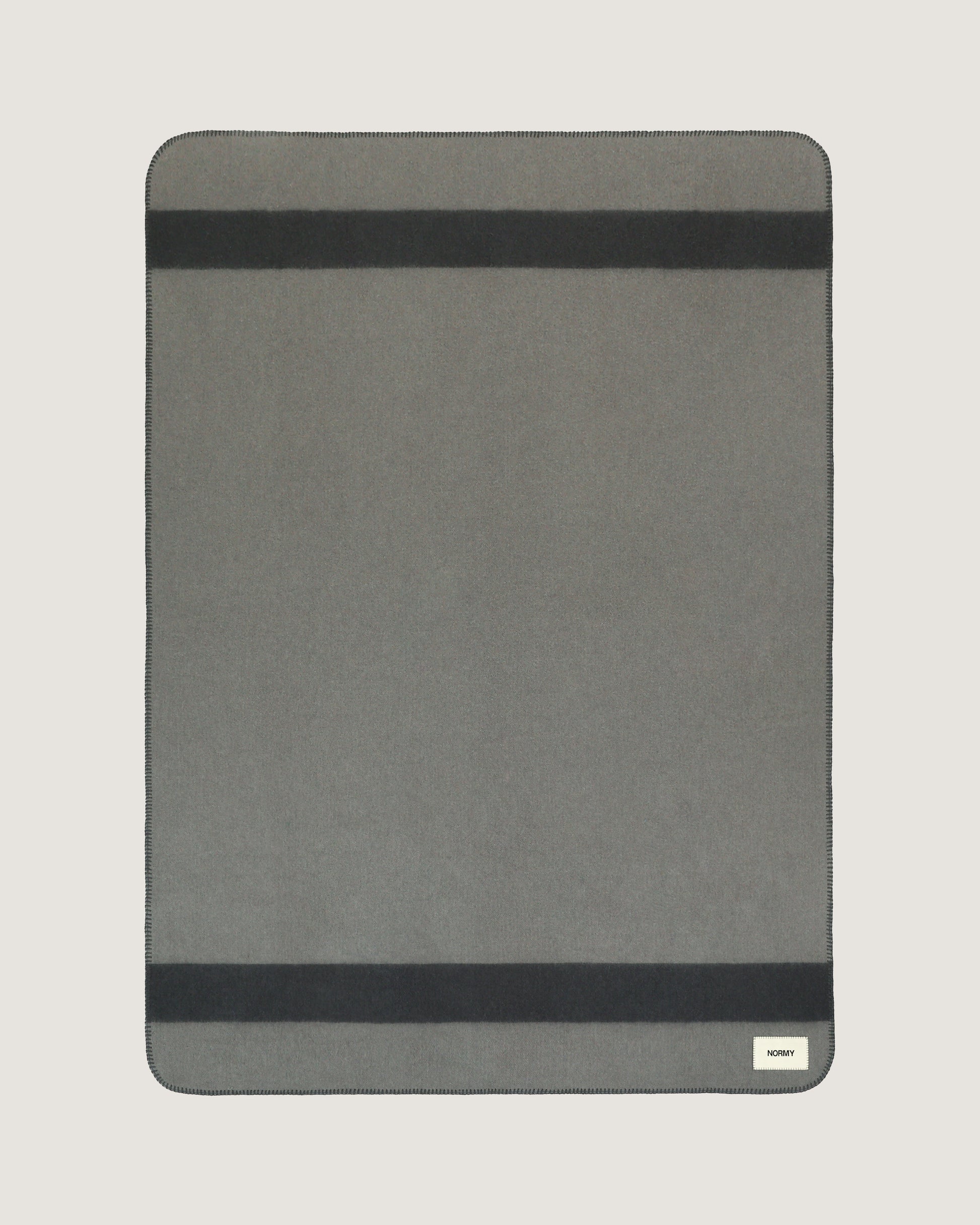 Merino wool blanket in peak/caviar flat against a neutral background