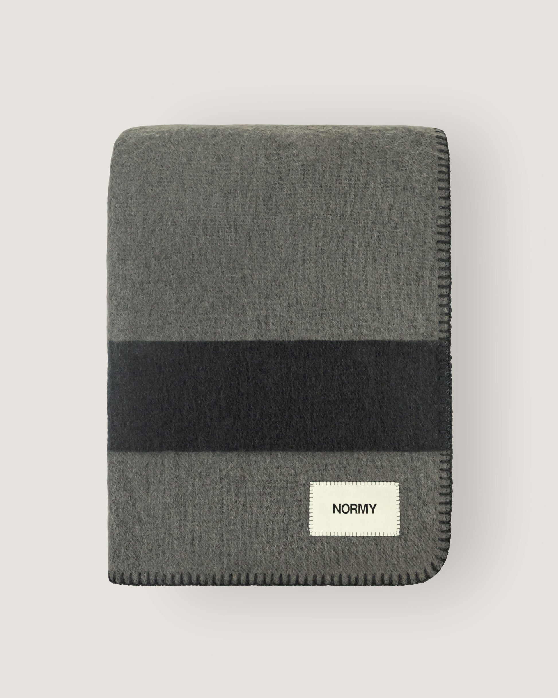 Merino wool blanket in peak/caviar folded against a neutral background