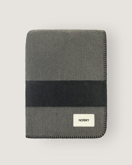 Merino wool blanket in peak/caviar folded against a neutral background