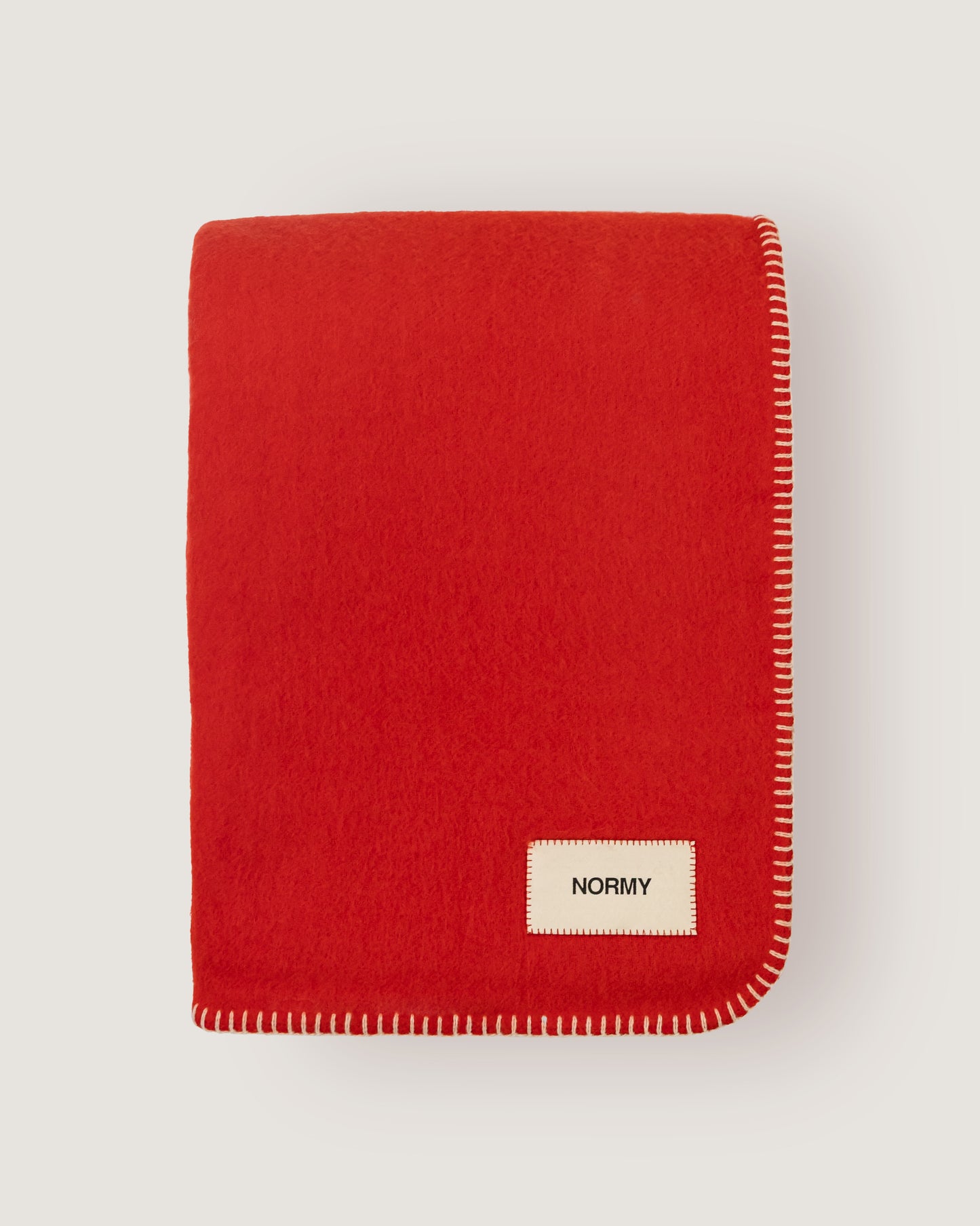 Merino wool blanket in poppy folded against a neutral background
